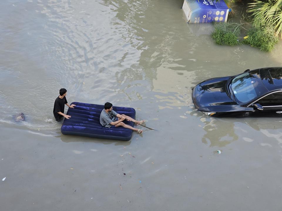 DUBAI, UNITED ARAB EMIRATES - APRIL 17: Two men use an inflatable bed to float above the water as downpour causes heavy flooding in Dubai, United Arab Emirates on April 17, 2024. (Photo by Stringer/Anadolu via Getty Images)