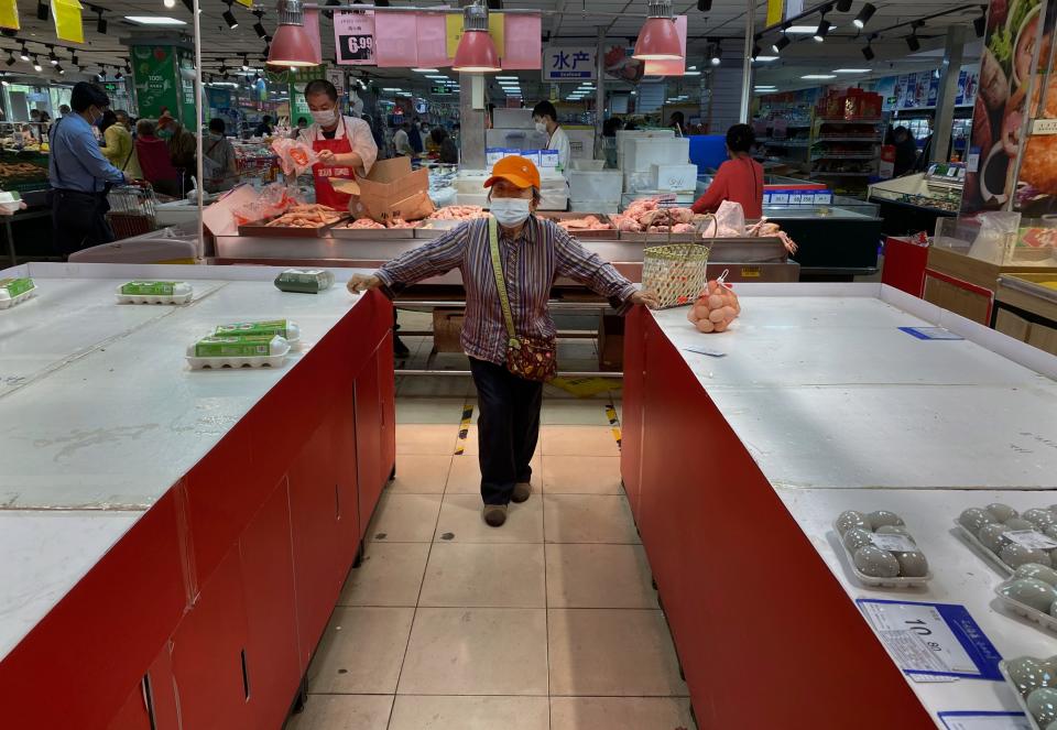 A woman stands between nearly empty displays for eggs after they were bought out at a supermarket in Chaoyang District on April 25, 2022 in Beijing, China.