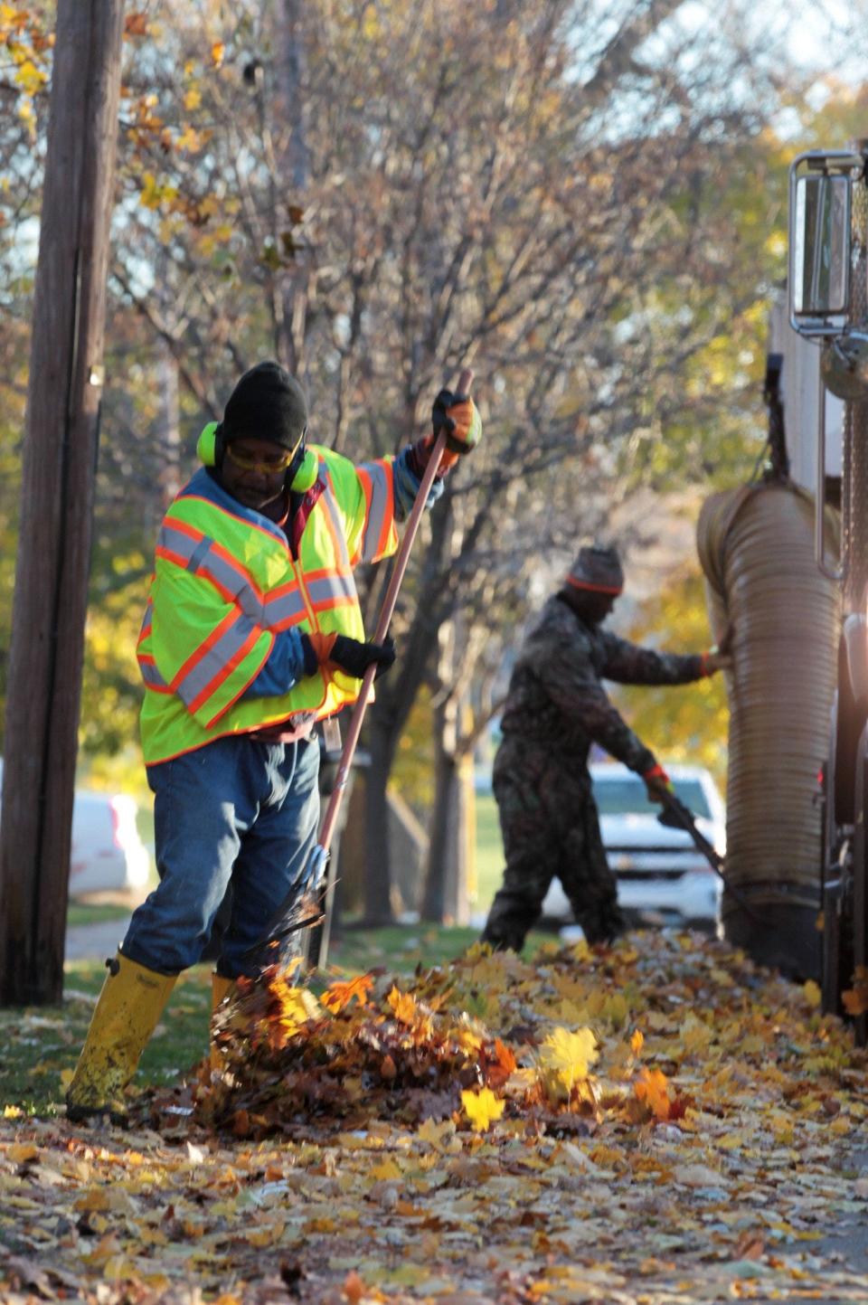 An Akron city worker rakes leaves as city crews work to clear public spaces.