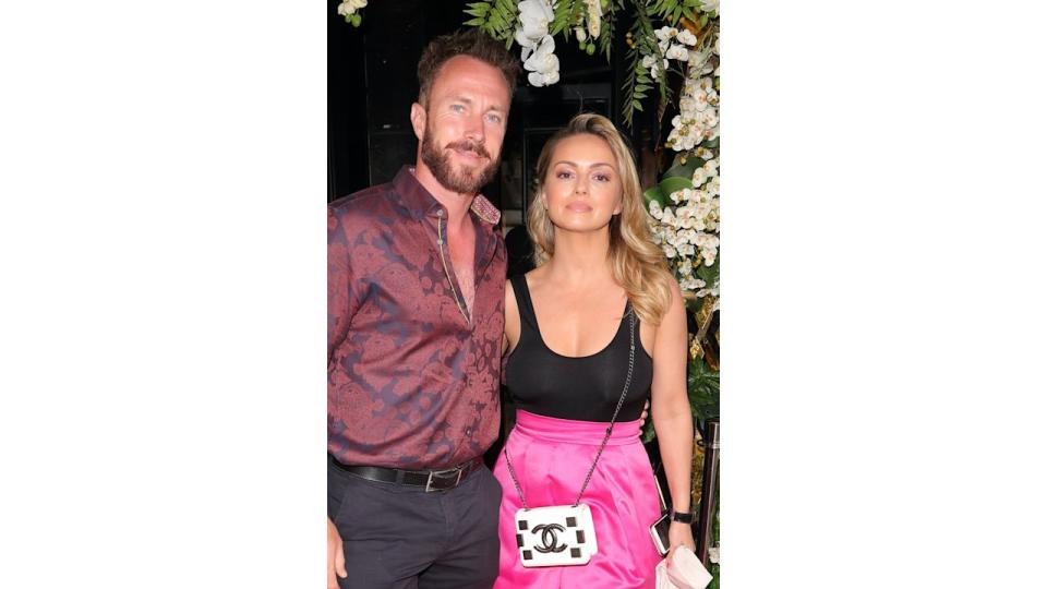 James Jordan in a red shirt and Ola Jordan in black and pink against the backdrop of white flowers