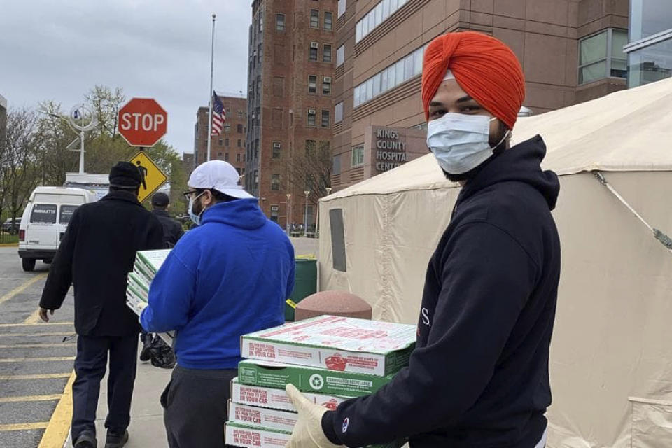 In this April 7, 2020, handout photo, Japneet Singh, right, delivers pizza to health care workers at Kings County Hospital in the Brooklyn borough of New York. Singh estimates 1,000 pizzas were delivered to essential workers since the end of March. (Courtesy of the New York Sikh Council via AP)