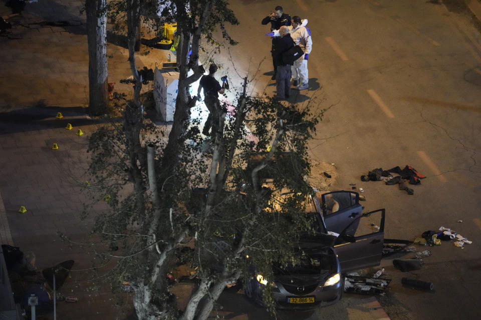 Israeli police inspect the scene of a shooting attack In Hadera, Israel, Sunday, March 27, 2022. A pair of gunmen killed two people and wounded four others in a shooting spree in central Israel before they were killed by police, according to police and medical officials. The identity of the gunmen was not immediately known, but police called them "terrorists," the term usually used for Arab assailants. (AP Photo/Ariel Schalit)