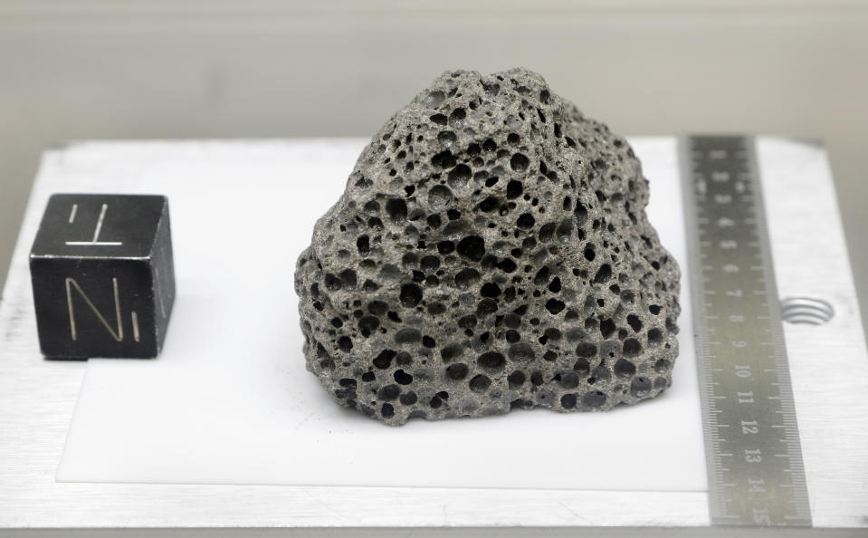 Collected during Apollo 15, a 3.5 billion years old basalt rock similar to rocks formed around Hawaii, is displayed in a pressurized nitrogen-filled examination case inside the lunar lab at the NASA Johnson Space Center Monday, June 17, 2019, in Houston. For the first time in decades, NASA is about to open some of the pristine samples and let geologists take a crack at them with 21st-century technology. (AP Photo/Michael Wyke)