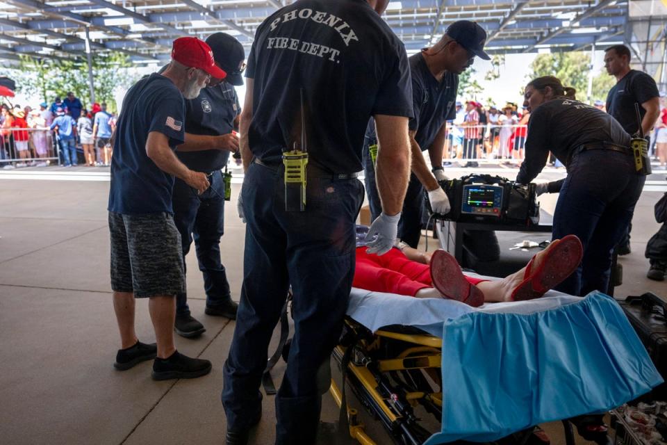 As temperatures reach 108 degrees Farenheit (42C), a woman is tended to for heat exhaustion as supporters line up before former US President and 2024 Republican presidential candidate Donald Trump participates in a town hall event (AFP via Getty Images)