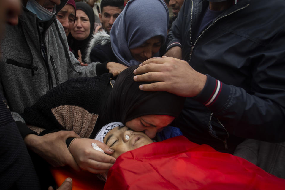 Relatives mourn the body of a 13-year-old Ali Abu Alia who was shot dead by Israeli military forces during clashes with a stone-throwing Palestinains during his funeral in al-Mughair village near the West Bank city of Ramallah, Saturday, Dec. 5, 2020. (AP Photo/Majdi Mohammed)