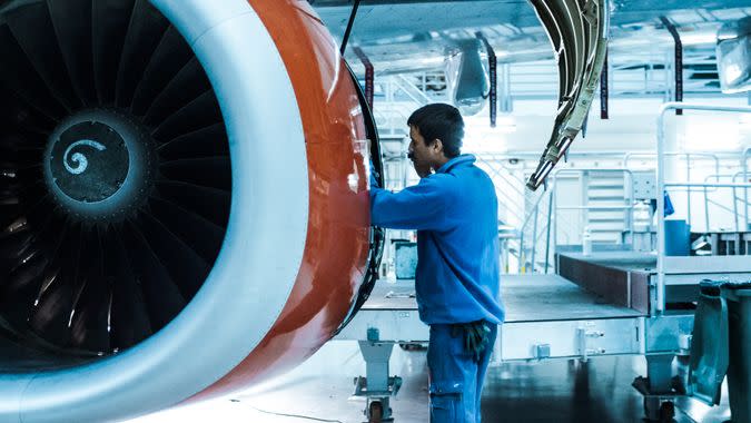 Aircraft maintenance mechanic inspects and tunes plane engine in a hangar.