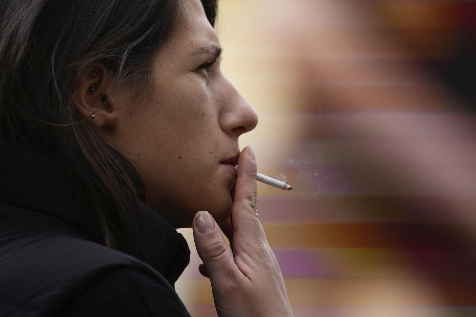 A woman smokes on a street, in London, Tuesday, April 16, 2024. A bold plan to ban anyone born after 2008 from ever legally buying cigarettes in Britain faces its first test in Parliament. The bold plan has divided the governing Conservatives, with some hailing its public health benefits and others condemning it as state overreach. (AP Photo/Kin Cheung)