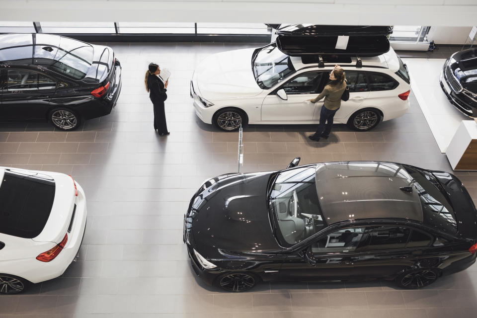 Two people examining cars inside a showroom, with five vehicles displayed around them