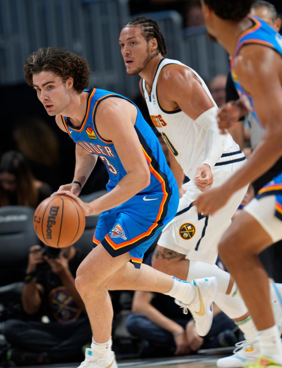 Thunder guard Josh Giddey, front, picks up the ball as Nuggets forward Aaron Gordon pursues in the first half.