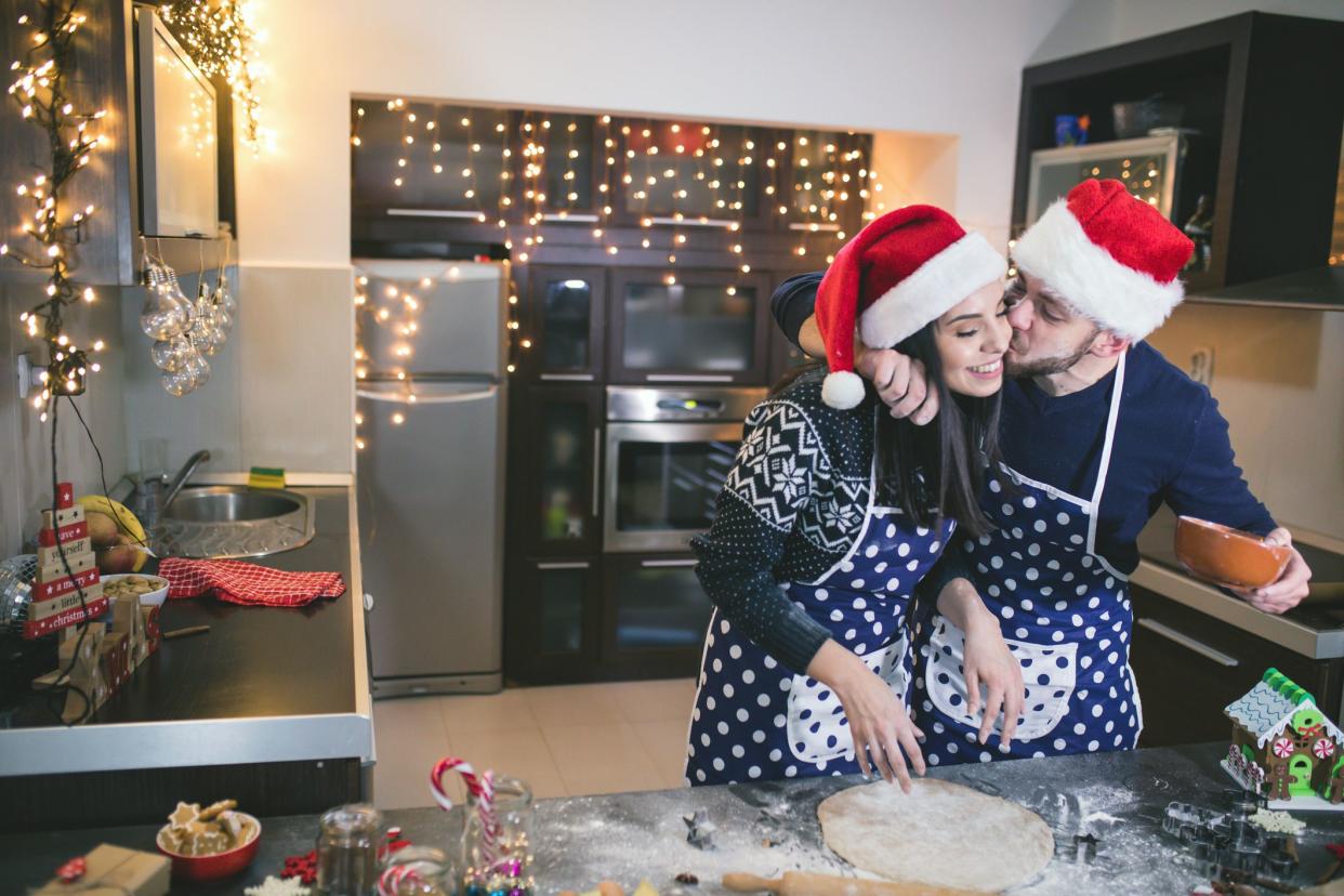 couple baking in santa's hats in the kitchen on christmas day