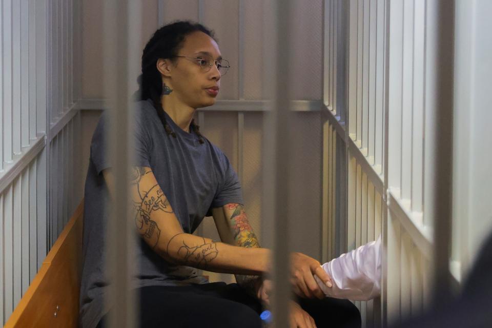 WNBA star Brittney Griner shakes hands with her lawyer in a Russian courtroom.