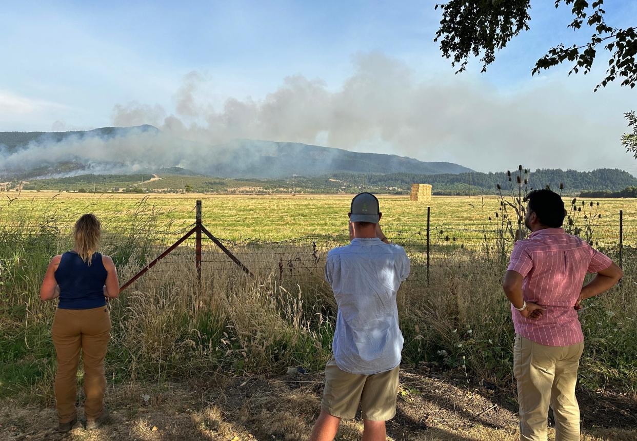 People watch a wildfire burn in the Coburg Hills east of the freeway from a rest area along Interstate 5 north of Eugene.