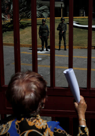 A supporter of Venezuelan opposition leader and self-proclaimed interim president Juan Guaido holds a document, regarding a proposed amnesty law for members of the military, police and civilians, as she explains it to the soldiers at the gate of Naval Command building in Caracas, Venezuela, January 27, 2019. REUTERS/Carlos Barria