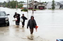 Residents wade through flood waters after an evacuation order following heavy rains caused flooding, closed roads, and forced evacuation in High River, Alta., Thursday, June 20, 2013.