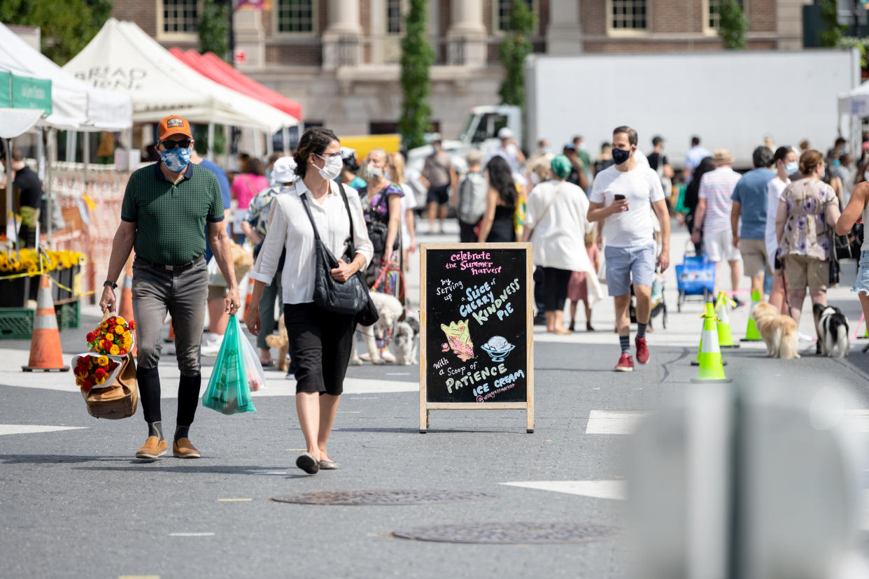 NEW YORK, NEW YORK - AUGUST 21: People wearing masks walk through Union Square's farmers market as the city continues Phase 4 of re-opening following restrictions imposed to slow the spread of coronavirus on August 21, 2020 in New York City. The fourth phase allows outdoor arts and entertainment, sporting events without fans and media production. (Photo by Alexi Rosenfeld/Getty Images)