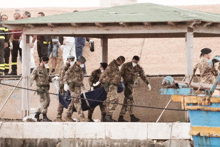 Italian soldiers carry the body of an asylum-seeker who died when a ship sank on October 3, 2013 in Lampedusa harbour