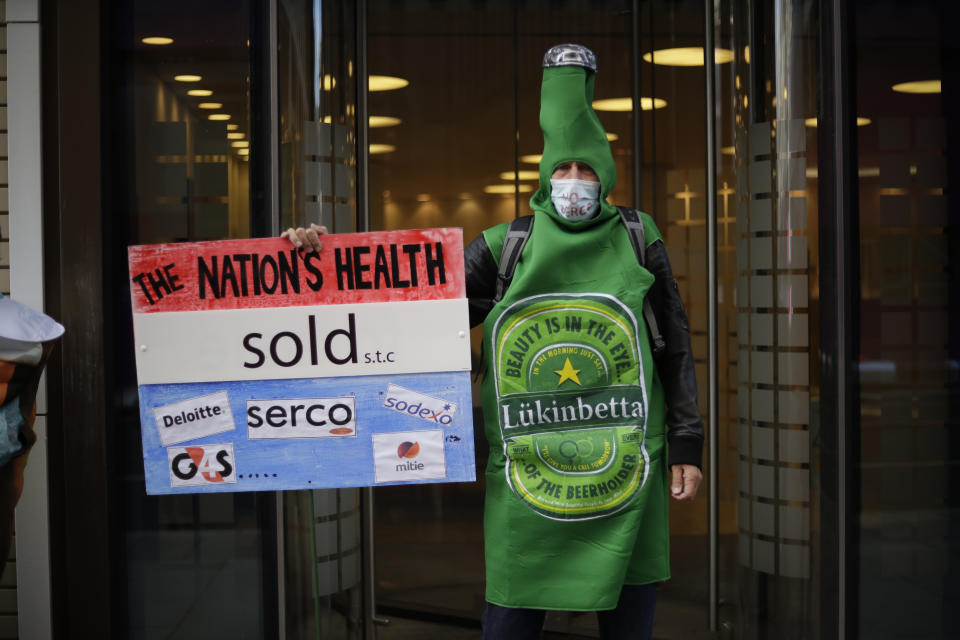 A protester takes part in a demonstration outside the Department of Health and Social Care office in London, over the private company Serco's handling of the British government's coronavirus test, track and trace system, Friday, Sept. 25, 2020. The protesters were on Friday calling for the test, track and trace system to be carried out by local public health teams who work closely with Britain's National Health Service. (AP Photo/Matt Dunham)