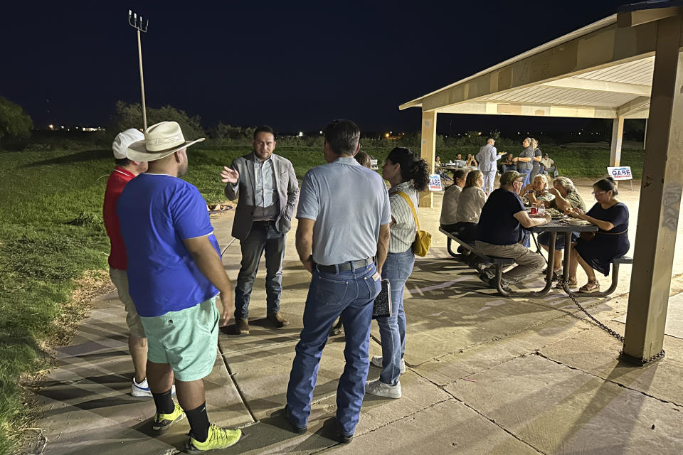 Rep. Gabe Vasquez, D-N.M., holds up a hand as he talks to guests at a "carne asada" campaign picknick, Tuesday, Aug. 20, 2024, in Chaparral, N.M., one of the region's oldest unincorporated "colonias" communities where many migrant workers settled over the past century on cheap plots of land, often with limited access to water or electricity. Vasquez touts his knowledge of the border region as the U.S.-born son of immigrants while seeking reelection in a rematch against former Republican Congresswoman Yvette Herrell. (AP Photo/Morgan Lee)