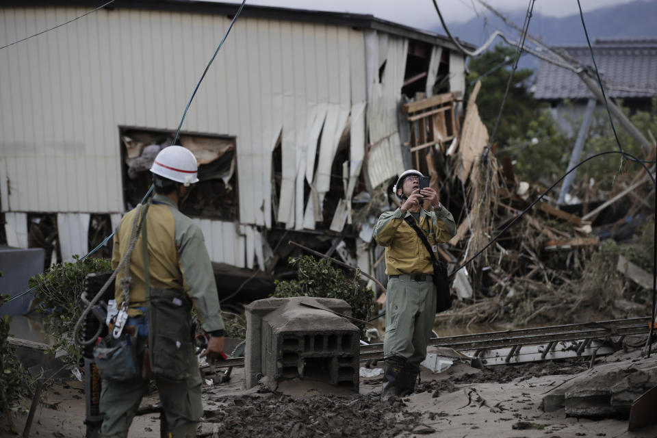 Workers survey damages in a neighborhood devastated by Typhoon Hagibis Tuesday, Oct. 15, 2019, in Nagano, Japan. More victims and more damage have been found in typhoon-hit areas of central and northern Japan, where rescue crews are searching for people still missing. (AP Photo/Jae C. Hong)