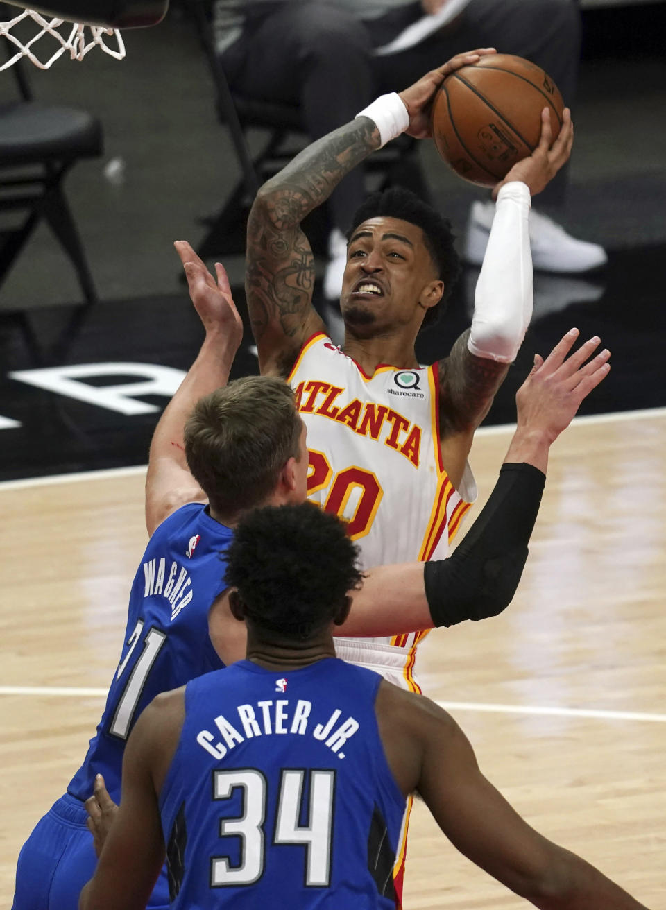 Atlanta Hawks forward John Collins (20) shoots over Orlando Magic forward Moritz Wagner (21) and Wendell Carter Jr., (34) in the second half of an NBA basketball game Thursday, May 13, 2021 in Atlanta. The Hawks defeated the Magic 116-93. (AP Photo/Tami Chappel)