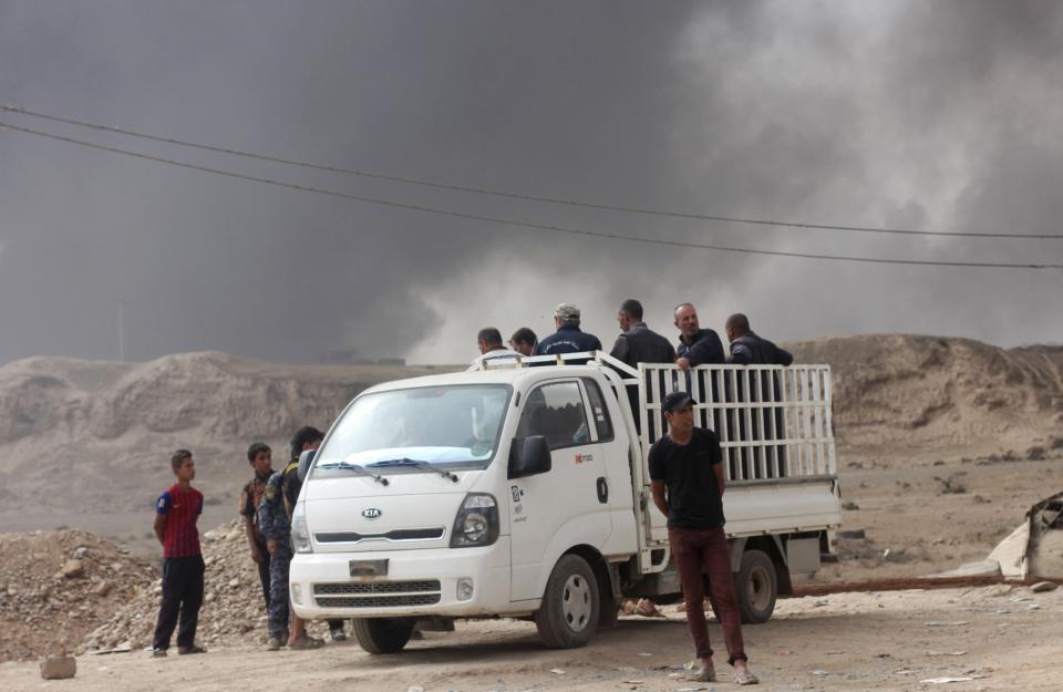 A group of IDPs prepare to be transported across the checkpoint by ISF in Qayyara north. (Photo: Ash Gallagher for Yahoo News)