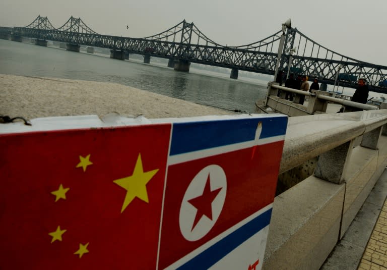 The Chinese and North Korean flags attached to a railing as trucks carrying Chinese-made goods cross into North Korea on the Sino-Korean Friendship Bridge at the Chinese border town of Dandong on December 18, 2013