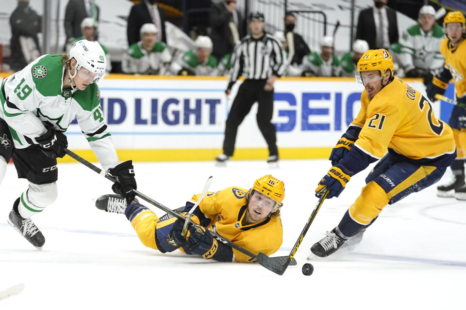 Nashville Predators center Rem Pitlick (16) reaches for the puck between teammate Nick Cousins (21) and Dallas Stars center Rhett Gardner (49) in the second period of an NHL hockey game Sunday, April 11, 2021, in Nashville, Tenn. (AP Photo/Mark Humphrey)