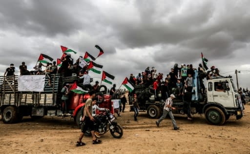 Palestinian protesters ride in trucks waving Palestinian flags as they bring tyres to be burnt for cover during clashes along the border with Israel east of Gaza City