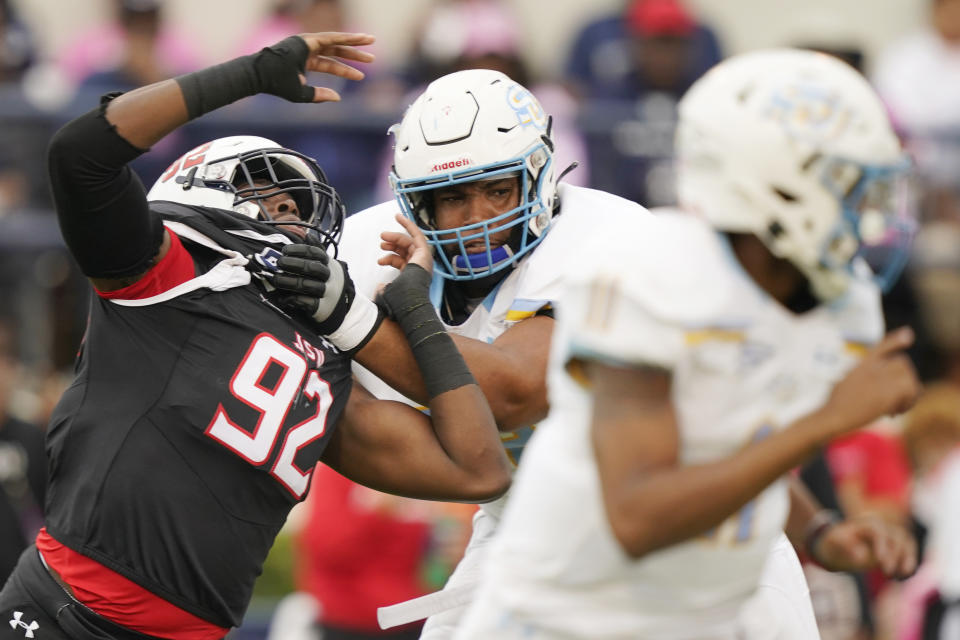 Jackson State defensive lineman Justin Ragin (92) is held by a Southern offensive lineman as he tries to tackle Southern University quarterback Besean McCray during the first half of an NCAA college football game in Jackson, Miss., Saturday, Oct. 29, 2022. (AP Photo/Rogelio V. Solis)