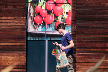 A customer walks out of a Whole Foods Market store in Santa Monica, California, U.S. March 19, 2018. REUTERS/Lucy Nicholson