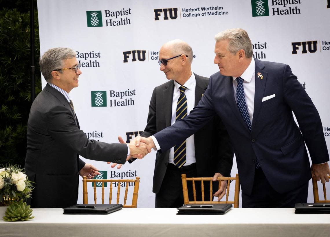 Juan Cendan, Dean of the Herbert Wertheim College of Medicine at FIU, left; Kenneth Jessell, FIU president, center; and Bo Boulenger, CEO of Baptist Health South Florida, shake hands during a signing ceremony for the clinical and academic partnership between Baptist Health and Florida International University on Tuesday, Nov. 28, 2023, at Baptist Health Miami Cancer Institute. Alie Skowronski/askowronski@miamiherald.com
