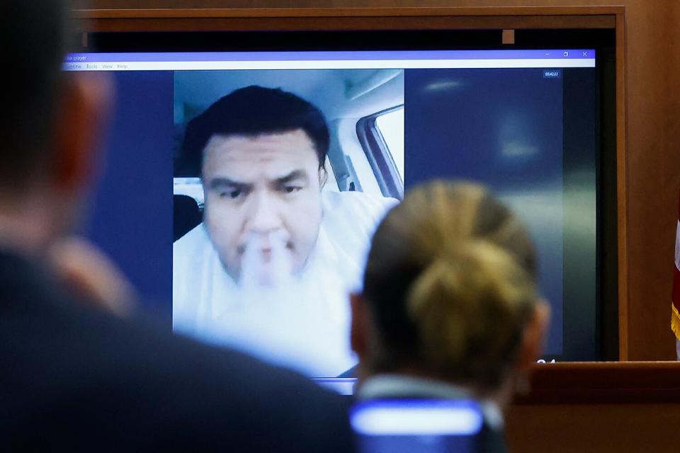 Actor Johnny Depp watches a pre-recorded deposition testimony of Alejandro Romero, who appears on a screen blowing vape smoke out of his nose, during Depp's defamation trial against his ex-wife Amber Heard, at the Fairfax County Circuit Courthouse in Fairfax, Virginia, on April 27, 2022. - US actor Johnny Depp sued his ex-wife Amber Heard for libel in Fairfax County Circuit Court after she wrote an op-ed piece in The Washington Post in 2018 referring to herself as a 