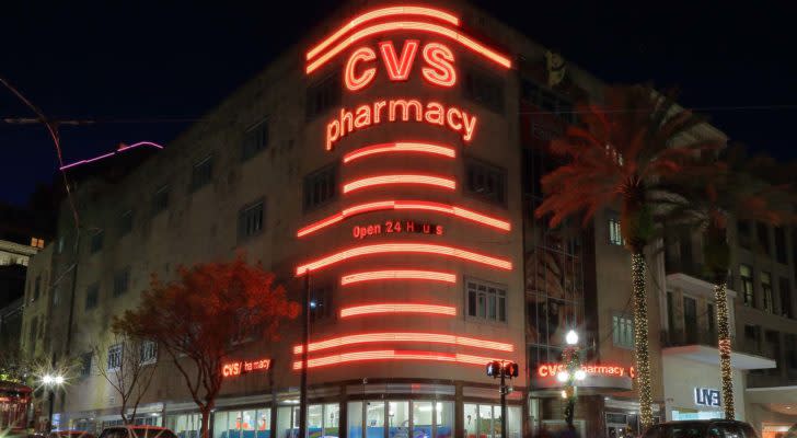 A photo of a CVS sign in neon on city building corner.