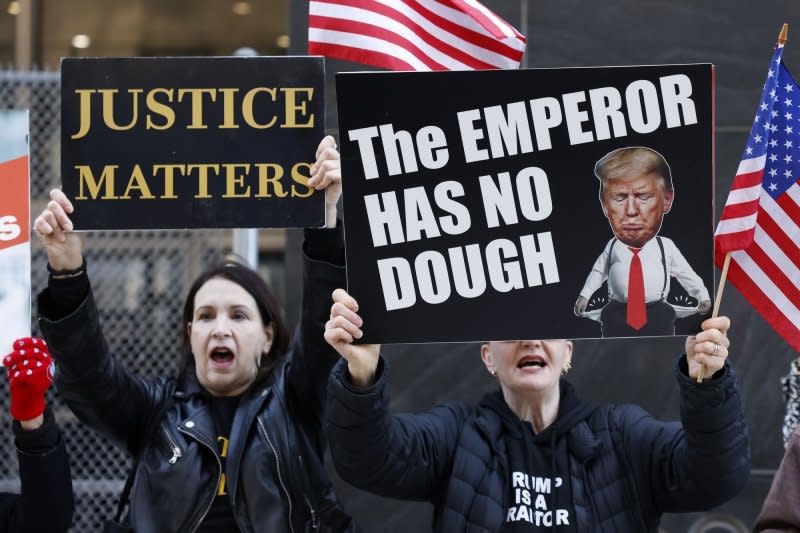 Protesters hold signs outside after former president Donald Trump arrives at Manhattan Criminal Court. Photo by John Angelillo/UPI