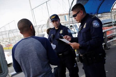 U.S. Customs and Border Protection officers inspect documents from a Honduran migrant seeking asylum at Paso del Norte International border bridge, in this picture taken from Ciudad Juarez