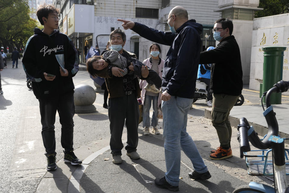 A man carrying a child is directed away from an area closed off during a visit by former Taiwan President Ma Ying-jeou to the John Rabe Former Residence in Nanjing, in eastern China's Jiangsu province, Tuesday, March 28, 2023. Former Taiwan President Ma Ying-jeou began a 12-day tour of China with a symbolism-laden visit to the mausoleum where the founding father of both China and Taiwan is entombed. (AP Photo/Ng Han Guan)