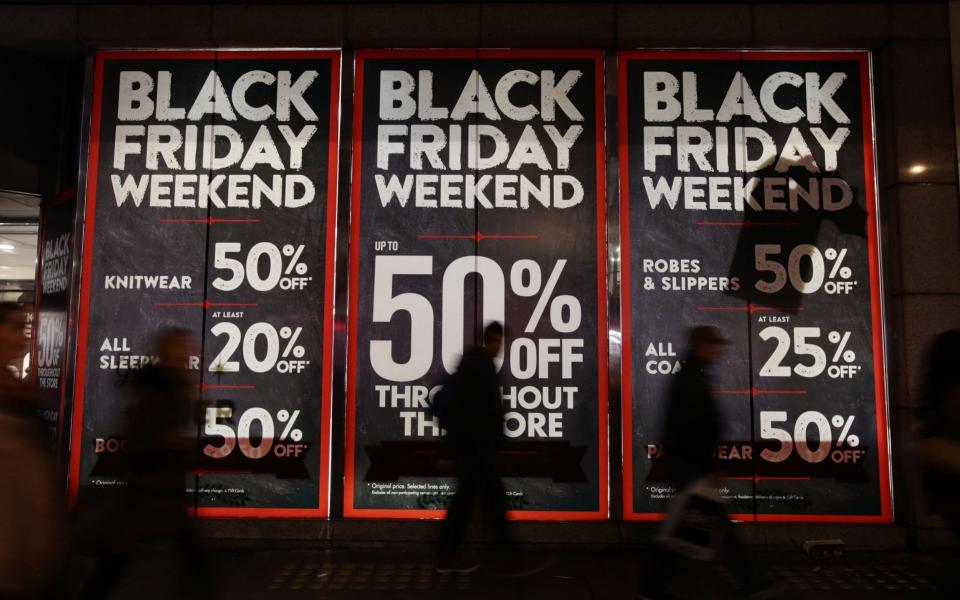 People walk past a Black Friday shop window advertisement in Oxford Street, London - PA