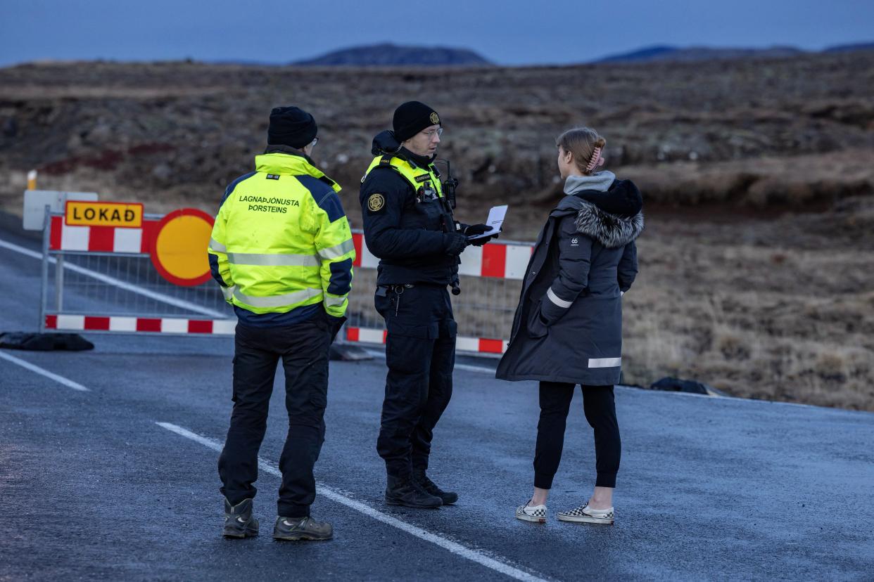 A police officer talks to a local resident on a road leading to the fishing town of Grindavik (REUTERS)