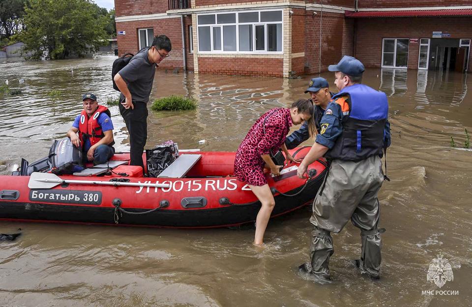 In this photo released by Russian Emergency Ministry Press Service on Sunday, Aug. 13, 2023, Emergency service workers give assistance in a flooded village in Primorye region, Russia's Far East after heavy downpours flooded villages in the region in the aftermath of Typhoon Khanun. Russian emergency officials say over 2,000 people have been evacuated from flooded areas of the Primorye region in the country's Far East. (Russian Emergency Ministry Press Service via AP)