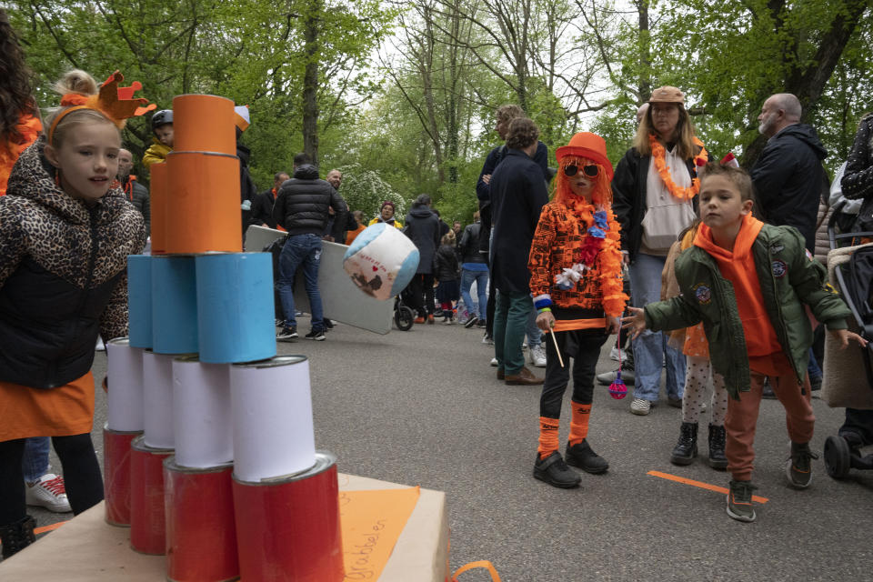 Orange-clad children play a Knock Down Cans game during King's Day celebrations in Amsterdam, Netherlands, Wednesday, April 27, 2022. After two years of celebrations muted by coronavirus lockdowns, the Netherlands marked the 55th anniversary of King Willem-Alexander of the House of Orange with street parties, music festivals and a national poll showing trust in the monarch ebbing away. (AP Photo/Peter Dejong)