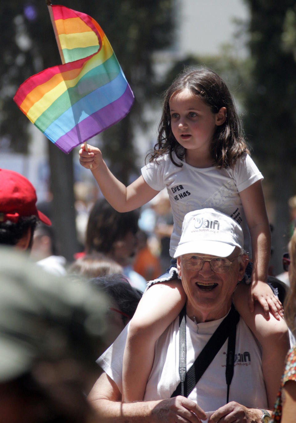 An Israeli girl sits on a relative's shoulders waving the rainbow flag, the international symbol of gay pride, during the annual Gay Pride parade along the streets of Tel Aviv on June 6, 2008. The parade has been taking place every year in the city since 1998. AFP PHOTO/JACK GUEZ