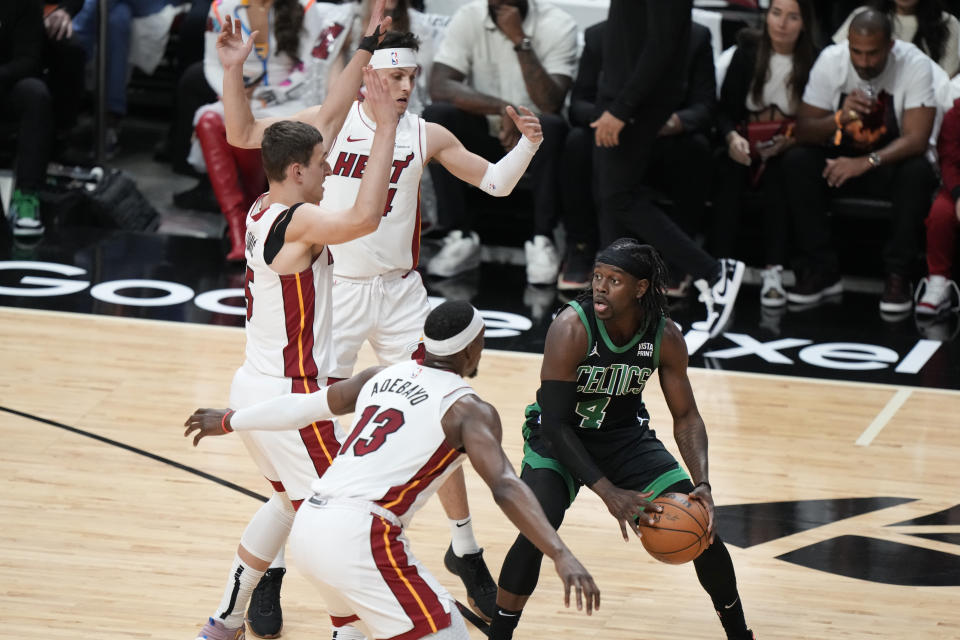 Boston Celtics guard Jrue Holiday (4) looks for an opening past Miami Heat center Bam Adebayo (13) forward Nikola Jovic, far left, and guard Tyler Herro, rear, during the first half of Game 3 of an NBA basketball first-round playoff series, Saturday, April 27, 2024, in Miami. (AP Photo/Wilfredo Lee)