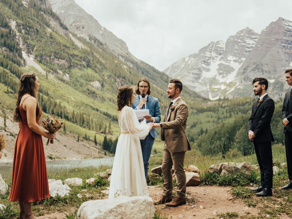 abi and her husband getting married in maroon bells amphitheater with their officiant speaking behind them