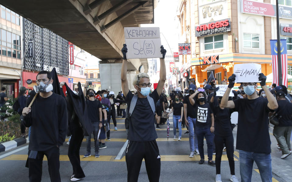 Protesters hold placards during a demonstration demanding the prime minister step down near the Independence Square in Kuala Lumpur, Saturday, July 31, 2021. Hundreds of black-clad Malaysian youths have rallied in the city center, demanding Prime Minister Muhyiddin Yassin resign for mismanaging the coronavirus pandemic that has worsened. (AP Photo/FL Wong)