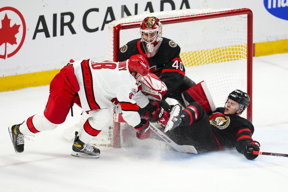 Carolina Hurricanes center Jack Drury (18) and Ottawa Senators defenseman Jacob Bernard-Docker (24) crash into Ottawa Senators goaltender Mads Sogaard (40) during the first period of an NHL hockey game in Ottawa, Ontario, Monday, April 10, 2023. (Sean Kilpatrick/The Canadian Press via AP)