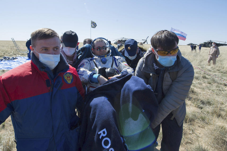 In this handout photo released by Gagarin Cosmonaut Training Centre (GCTC), Roscosmos space agency, rescue team members carry Russian cosmonaut Oleg Skripochka shortly after the landing of the Russian Soyuz MS-15 space capsule near Kazakh town of Dzhezkazgan, Kazakhstan, Friday, April 17, 2020. An International Space Station crew has landed safely after more than 200 days in space. The Soyuz capsule carrying NASA astronauts Andrew Morgan, Jessica Meir and Russian space agency Roscosmos' Oleg Skripochka touched down on Friday on the steppes of Kazakhstan. (Andrey Shelepin, Gagarin Cosmonaut Training Centre (GCTC), Roscosmos space agency, via AP)