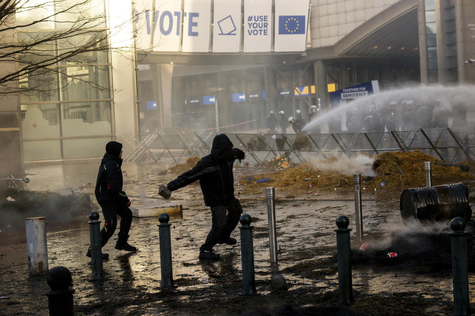 People throw stones towards anti riot police during a protest by farmers outside the European Parliament as European leaders meet for an EU summit in Brussels, Thursday, Feb. 1, 2024. European Union leaders meet in Brussels for a one day summit to discuss the revision of the Multiannual Financial Framework 2021-2027, including support for Ukraine. (AP Photo/Thomas Padilla)