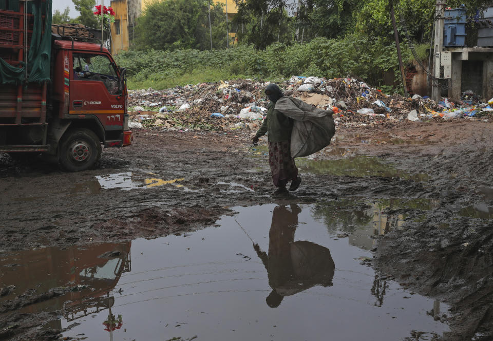 An Indian rack picker protect her face with a cloth as a precaution against the coronavirus and searches for reusables at a market in Hyderabad, India, Thursday, Sept. 17, 2020. India's total of coronavirus infections passed 5 million Wednesday, still soaring and testing the feeble health care system in tens of thousands of impoverished towns and villages. (AP Photo/Mahesh Kumar A.)