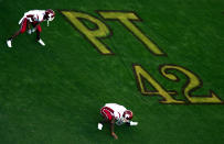 Members of the Washington State Cougars stretch in front of a memorial painted on the field for Pat Tillman #42 of the Arizona Cardinals during their Pac-10 game against the Arizona Sun Devils at Sun Devil Stadium/Frank Kush Field on November 13, 2004 in Tempe, Arizona. (Photo by Donald Miralle/Getty Images)