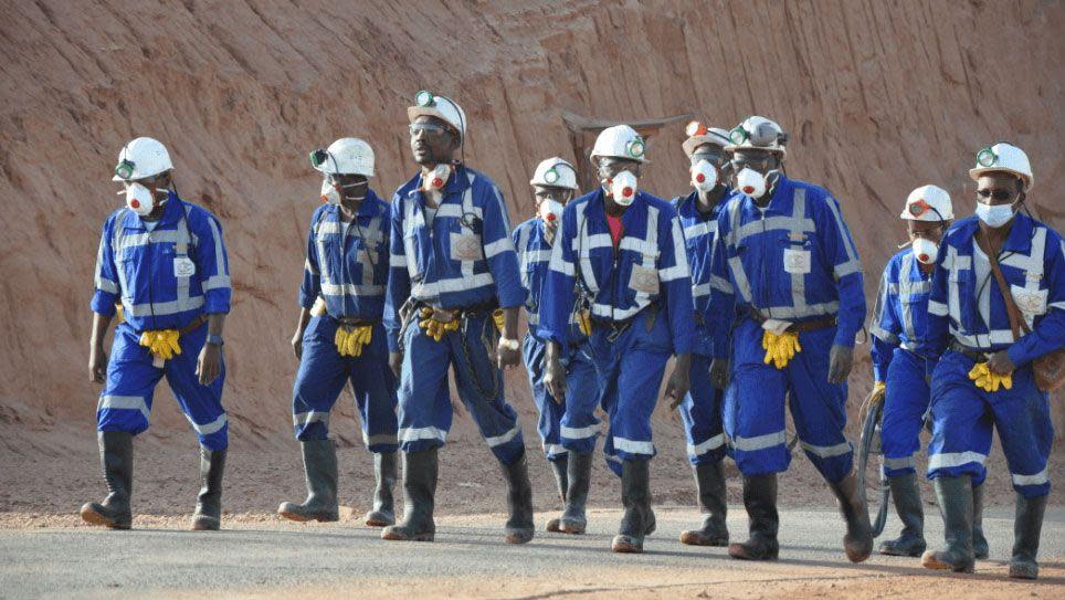 A group of Orano miners in Niger walking, wearing blue boiler suits